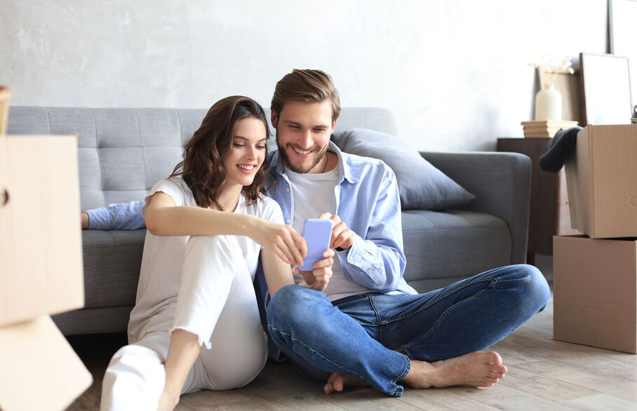 Two people sitting on the floor looking at their phone