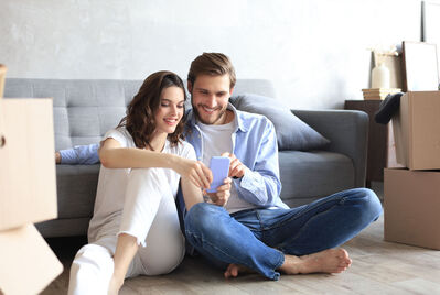 Two people sitting on the floor looking at their phone