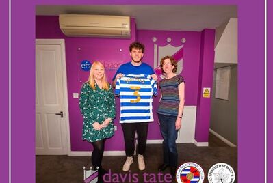Two Davis Tate employees posing with footballer Tom Holmes who is holding a signed t-shirt