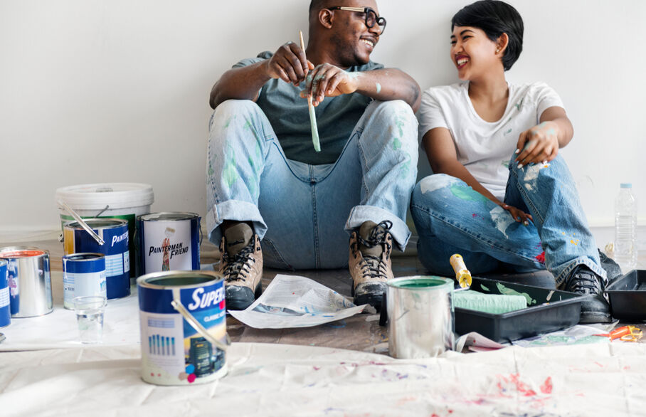 Two people sitting on the floor in front of paint cans