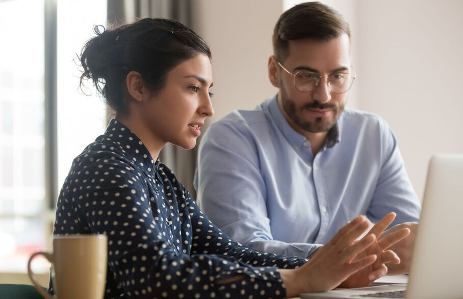 Two people sitting in front of a laptop