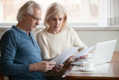 Two people looking at paper in front of a laptop