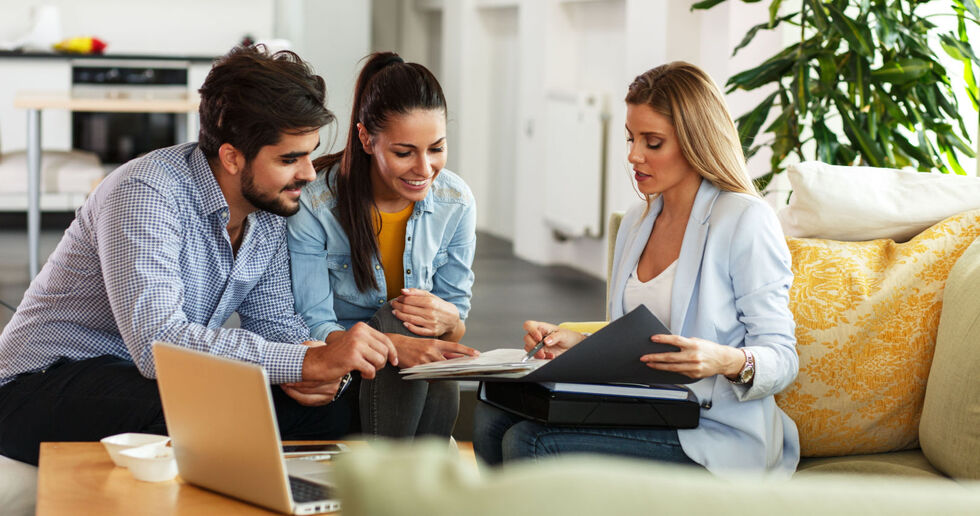 Female Estate agent talking to young couple on sofa
