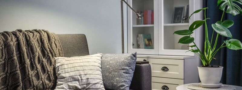 Couch with a comfy blanket reading light and a bookcase