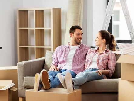 Couple on sofa, surrounded by moving boxes