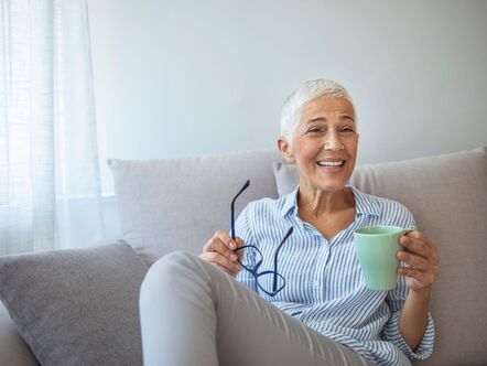 Happy lady on a couch with a glasses and a cup 