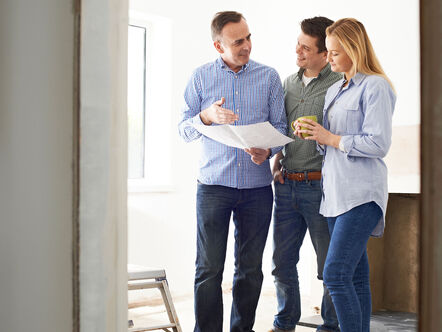 Three adults looking at plans