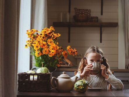 child with a bouquet of yellow flowers and a cup of tea