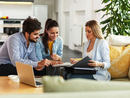 Couple with female estate agent in their home