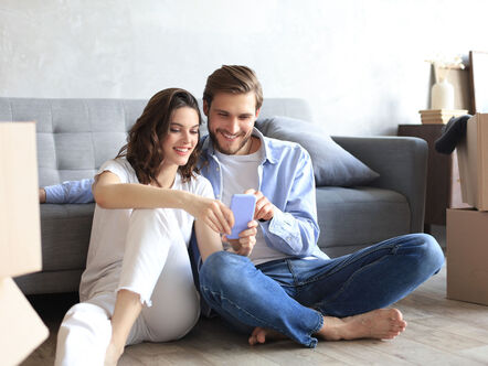 Couple sat in front room surrounded by boxes