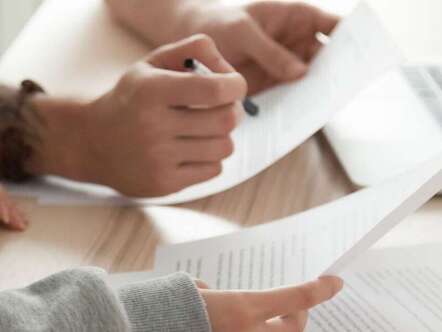 Two people looking at papers in front of a laptop